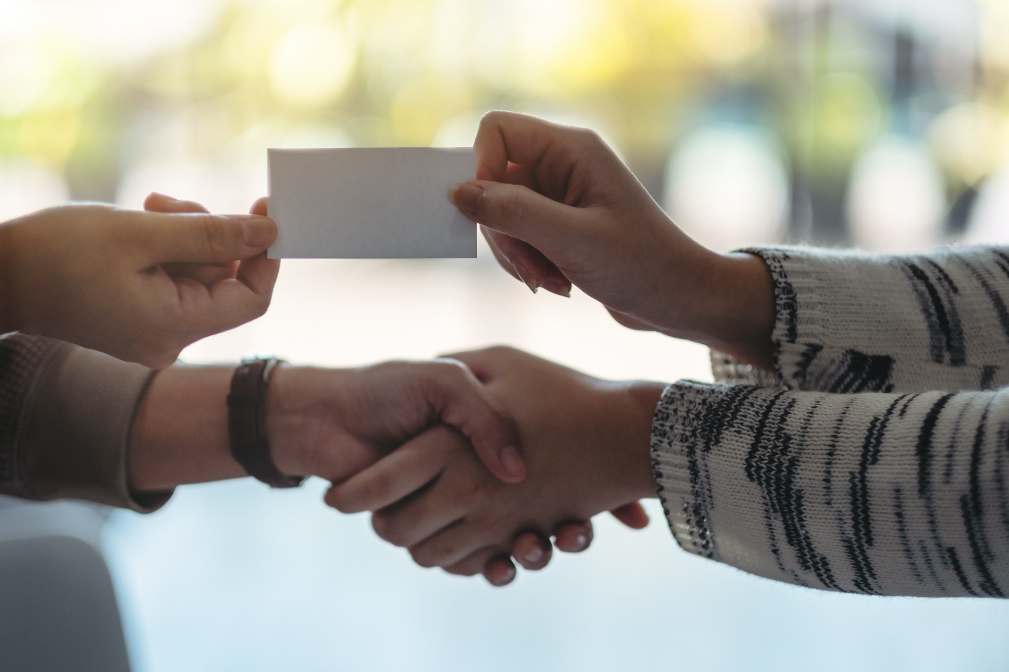 Two people shaking hands and exchanging empty business card